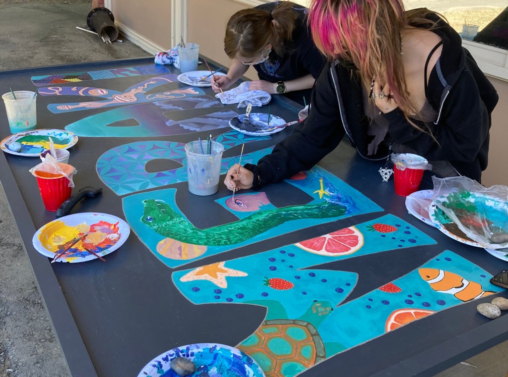 Students working on a school mural of their own design as led by NJA.